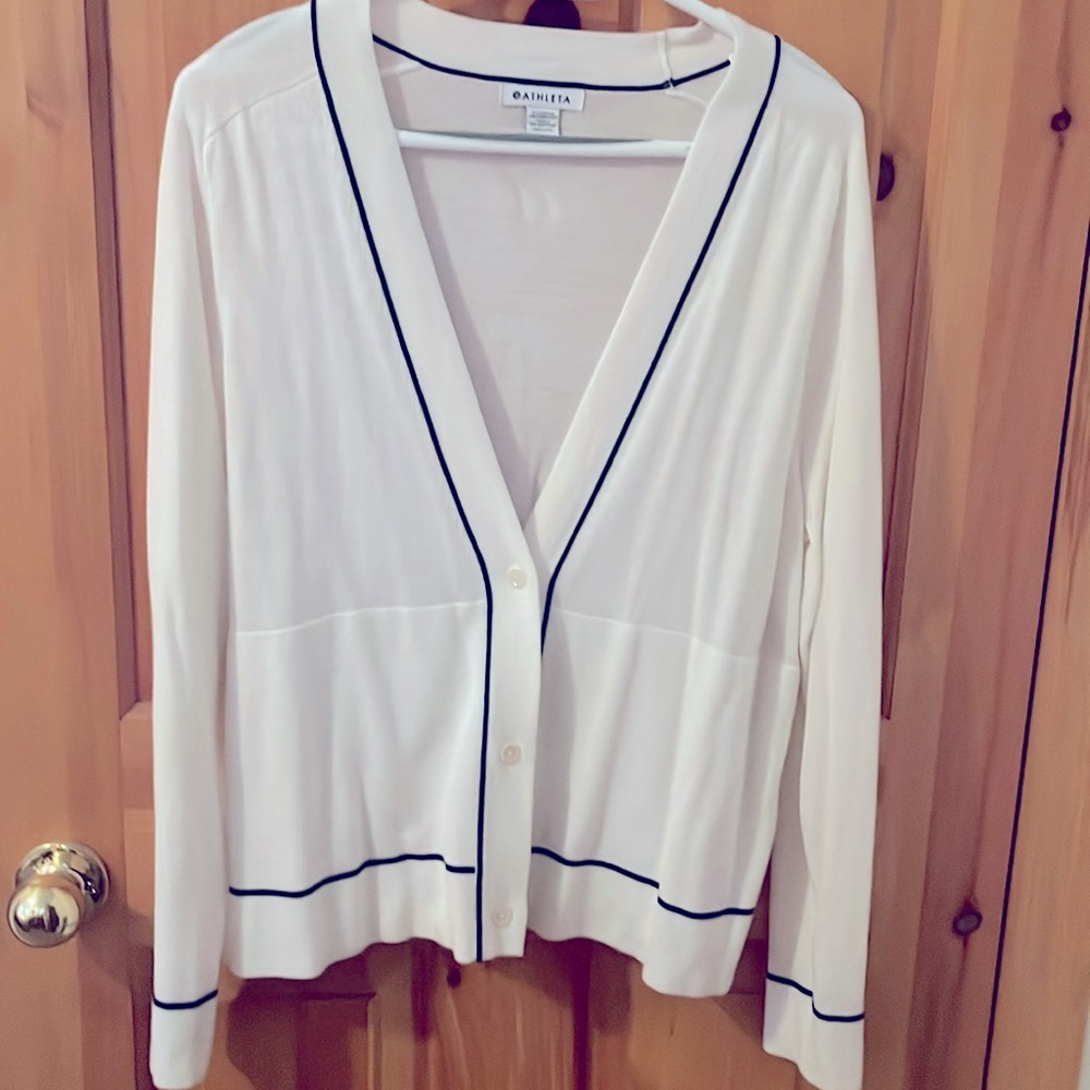 A white cardigan with navy blue trim.